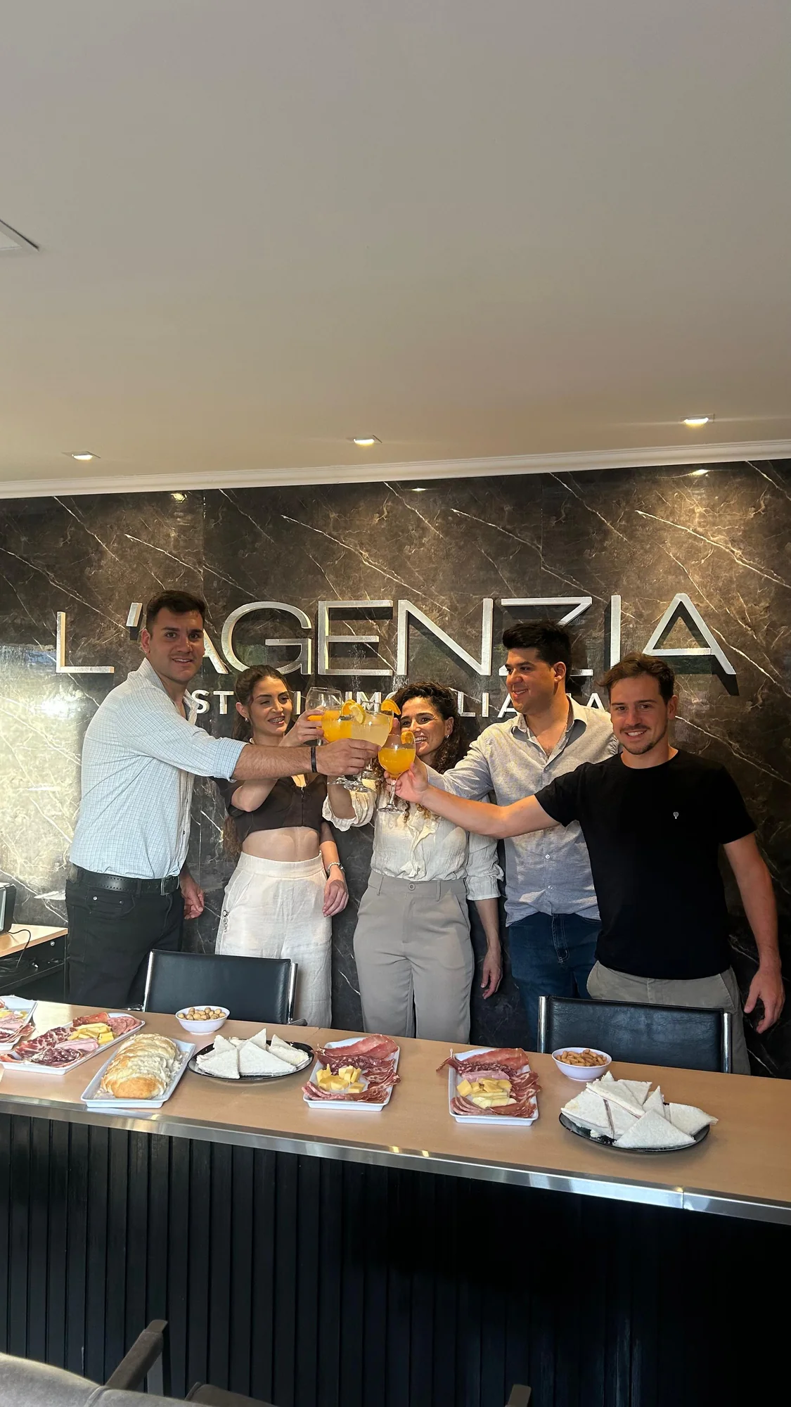 El equipo reunido frente al logo de L’Agenzia.